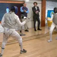 Two fencers face off on the set of a morning TV show.