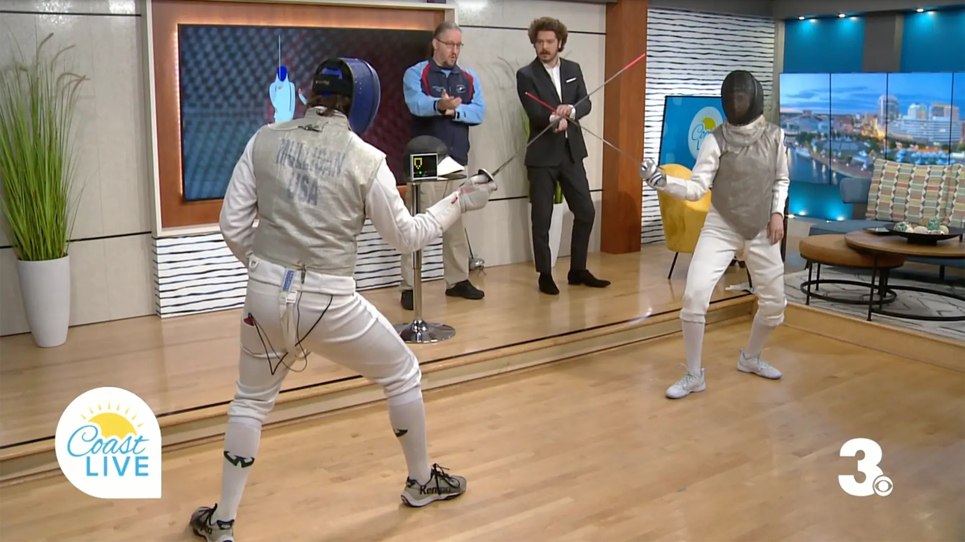 Two fencers face off on the set of a morning TV show.